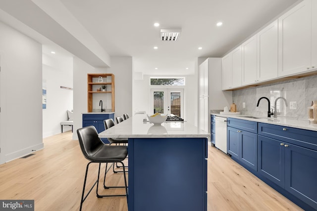 kitchen featuring white dishwasher, a kitchen island, white cabinetry, and sink