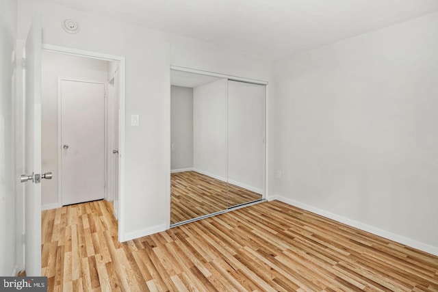 unfurnished bedroom with light hardwood / wood-style flooring and a closet