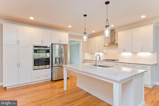 kitchen with light wood-type flooring, appliances with stainless steel finishes, a center island with sink, and wall chimney range hood