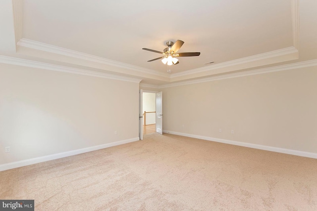 carpeted empty room with a tray ceiling, ceiling fan, and crown molding