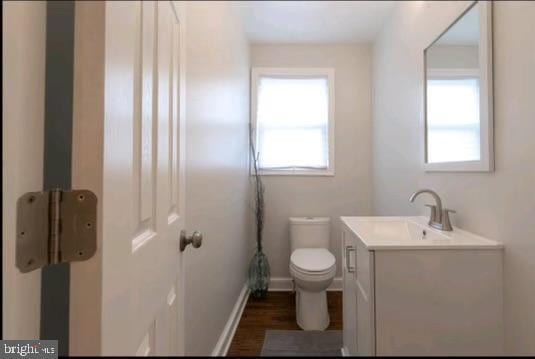 bathroom featuring vanity, hardwood / wood-style flooring, toilet, and a healthy amount of sunlight