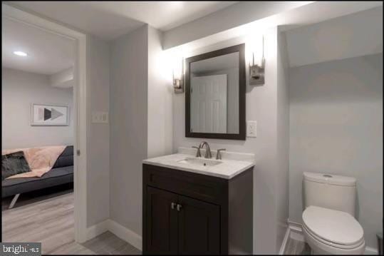 bathroom with hardwood / wood-style flooring, vanity, and toilet