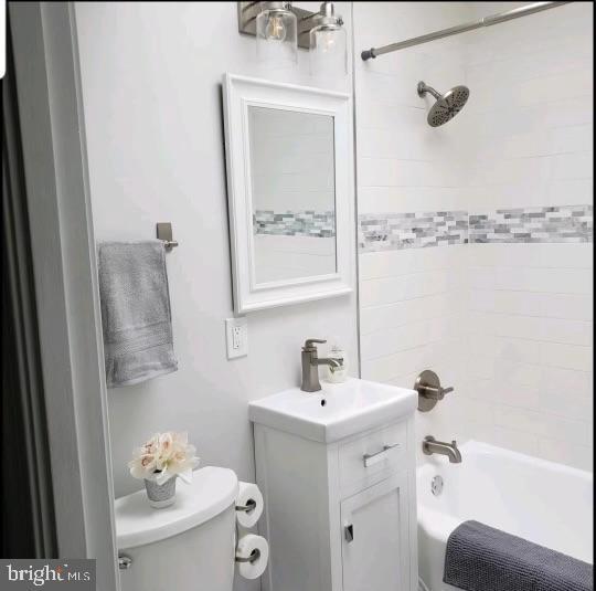 full bathroom featuring tiled shower / bath combo, toilet, and vanity