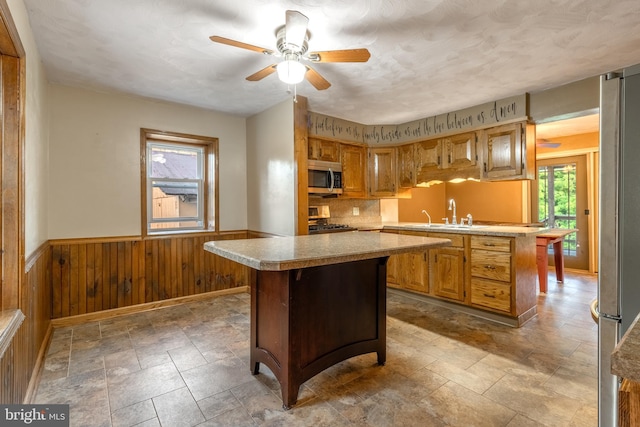 kitchen with a kitchen island, sink, stainless steel appliances, and wooden walls