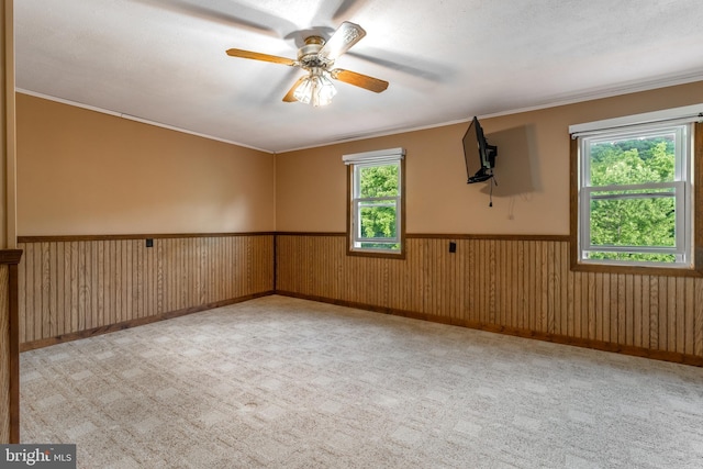 spare room featuring light colored carpet, ceiling fan, and ornamental molding