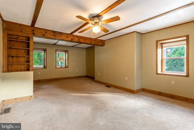 empty room featuring beam ceiling, ceiling fan, and light colored carpet