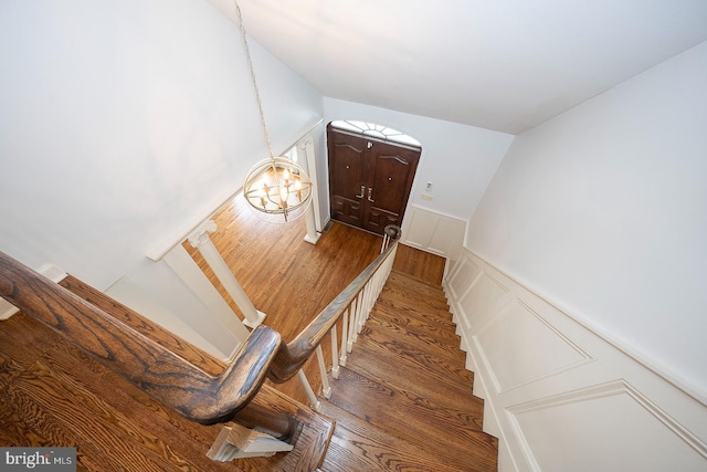 stairway featuring wood-type flooring and a notable chandelier