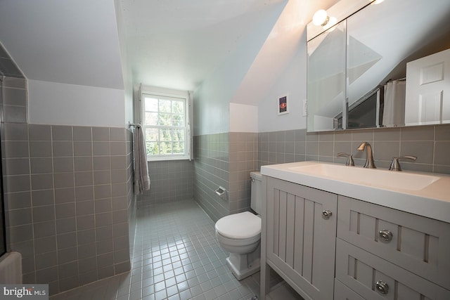 bathroom featuring toilet, vanity, tile patterned floors, and tile walls