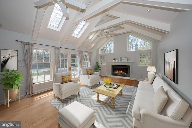 living room with beamed ceiling, ceiling fan, light wood-type flooring, and high vaulted ceiling