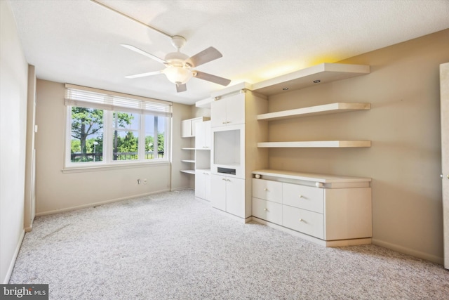 interior space with a textured ceiling, ceiling fan, and light carpet