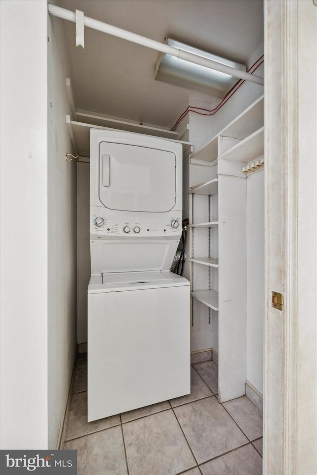 laundry room with stacked washer / drying machine and light tile patterned flooring