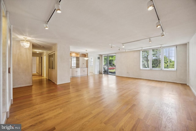 unfurnished living room featuring hardwood / wood-style floors, plenty of natural light, and a chandelier