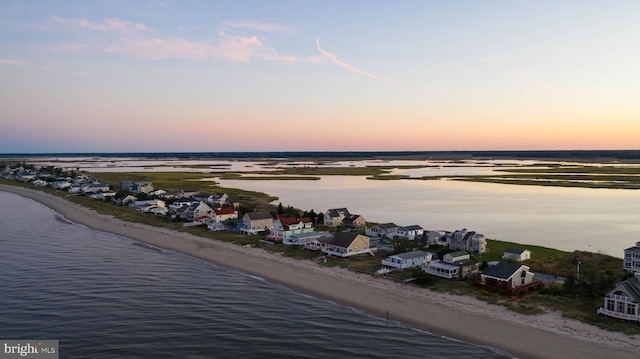 aerial view at dusk featuring a beach view and a water view