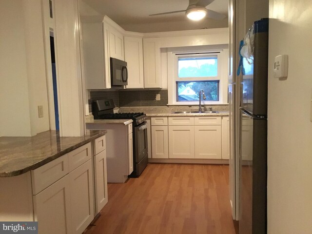 kitchen with light hardwood / wood-style flooring, white cabinets, ceiling fan, stainless steel range with gas stovetop, and sink