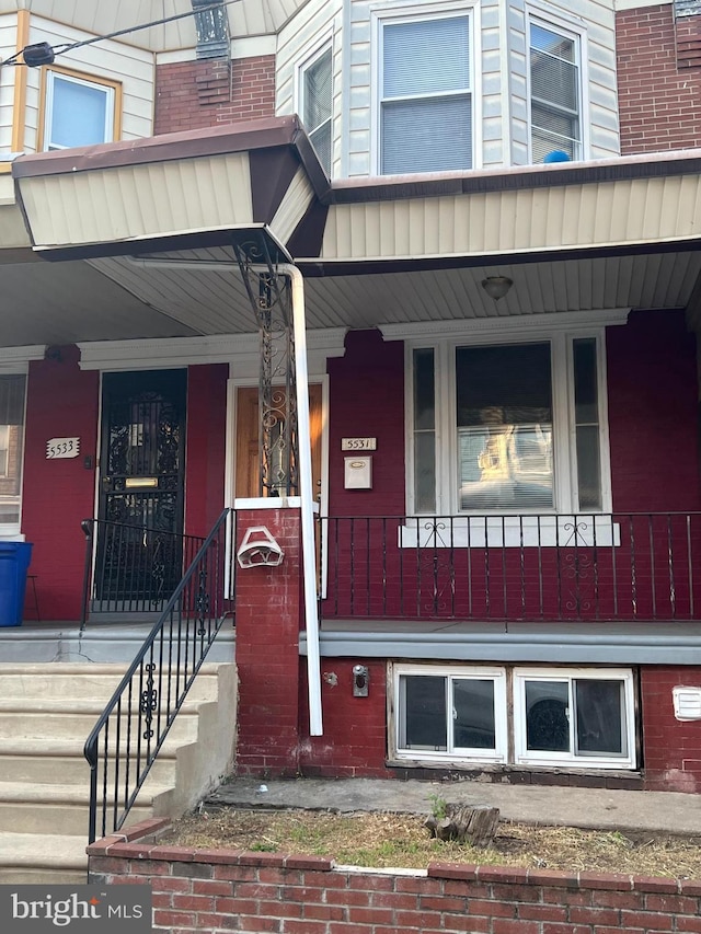 property entrance featuring covered porch and brick siding