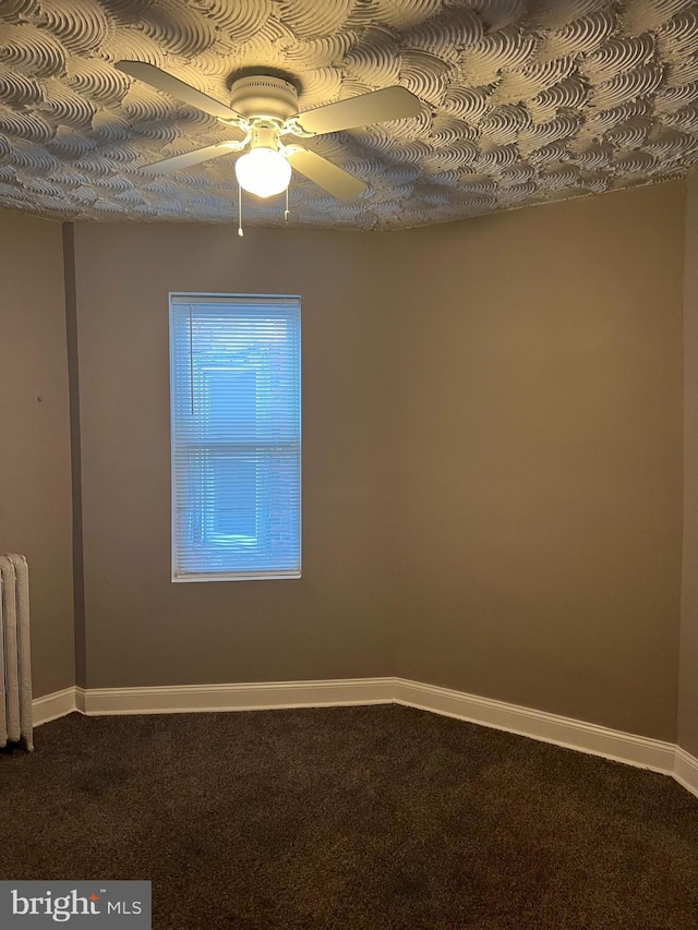 carpeted empty room featuring radiator and ceiling fan