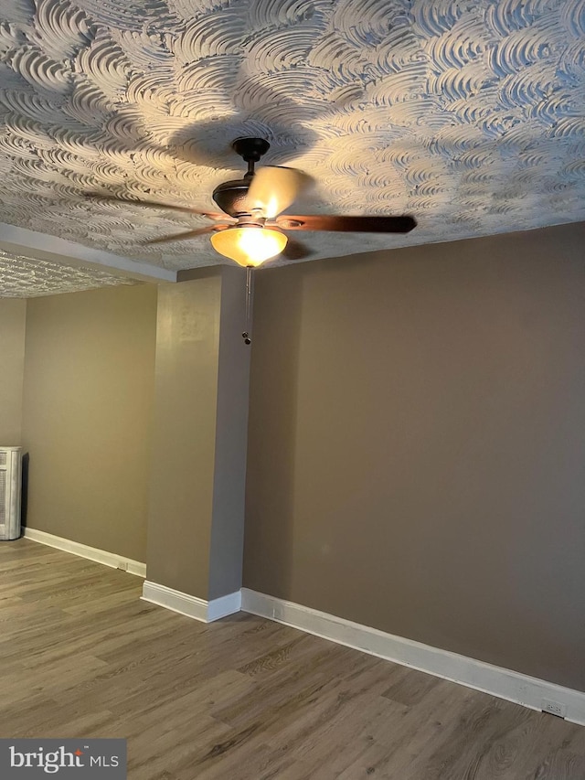 empty room with ceiling fan, baseboards, and wood finished floors