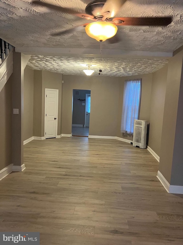 spare room with ceiling fan, a textured ceiling, baseboards, and wood finished floors