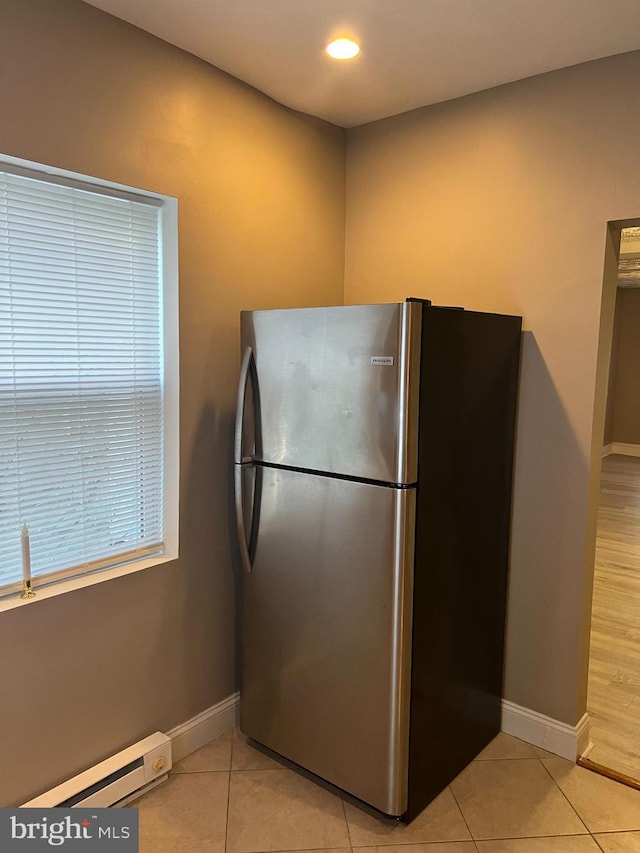 kitchen with stainless steel fridge, light tile patterned floors, and a baseboard heating unit