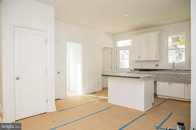 kitchen featuring a sink, a kitchen island, and white cabinets