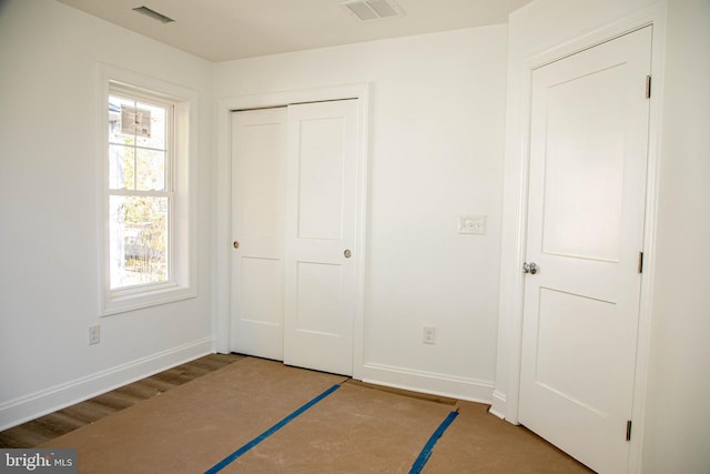 unfurnished bedroom with a closet, dark hardwood / wood-style floors, and multiple windows