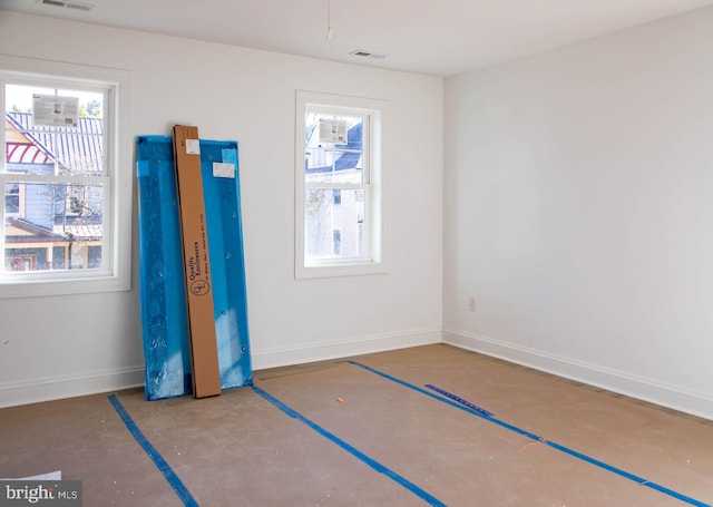 unfurnished bedroom featuring concrete floors, multiple windows, and baseboards