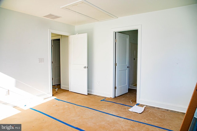 unfurnished bedroom featuring attic access, visible vents, and baseboards