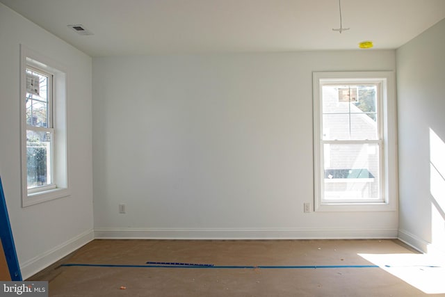 empty room featuring baseboards, visible vents, and a healthy amount of sunlight