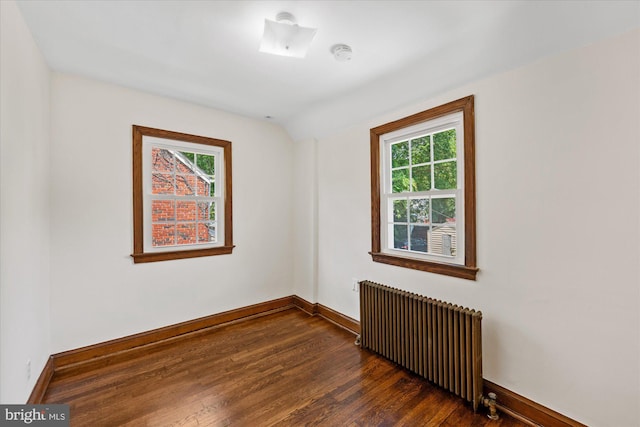 spare room featuring dark hardwood / wood-style flooring, radiator heating unit, and lofted ceiling