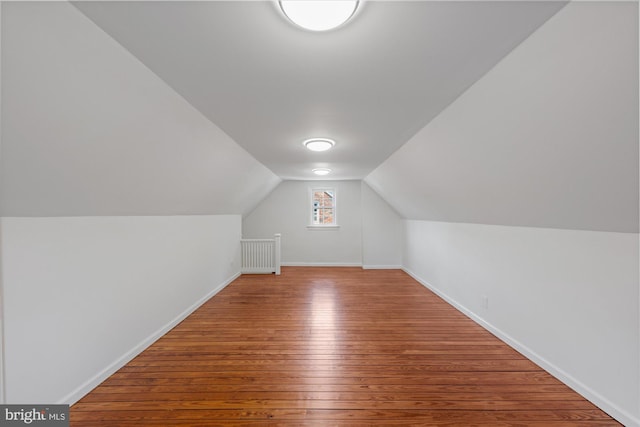 additional living space with hardwood / wood-style floors and vaulted ceiling