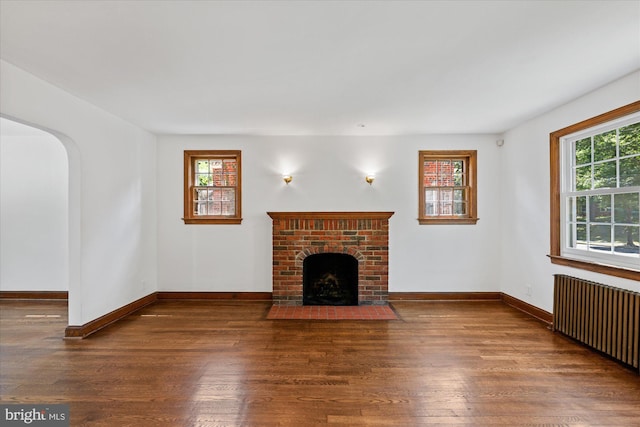 unfurnished living room featuring a fireplace, radiator heating unit, and dark hardwood / wood-style floors