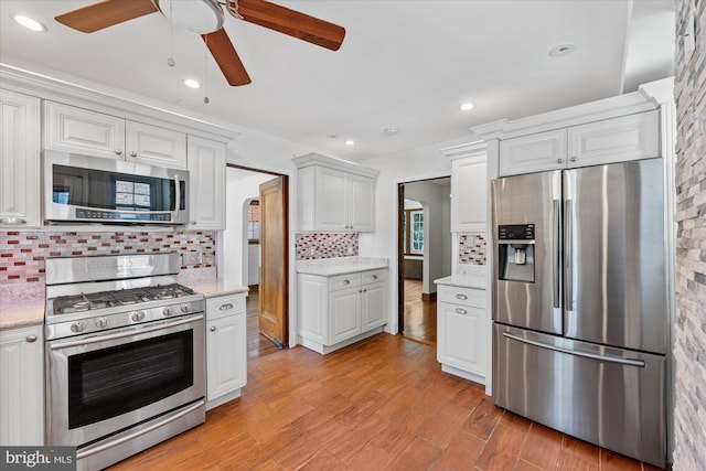 kitchen featuring white cabinets, appliances with stainless steel finishes, backsplash, and light hardwood / wood-style floors