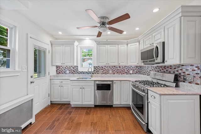 kitchen featuring tasteful backsplash, stainless steel appliances, sink, white cabinets, and radiator heating unit