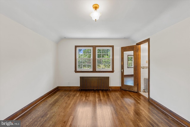 unfurnished room with dark hardwood / wood-style floors, radiator heating unit, and vaulted ceiling