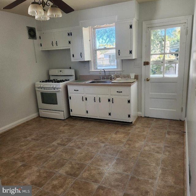 kitchen featuring white cabinetry, gas range gas stove, sink, and a wealth of natural light