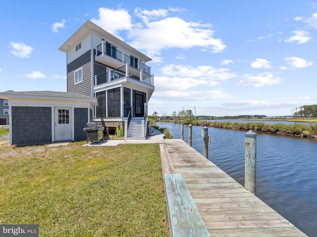 dock area with a water view, a balcony, and a lawn