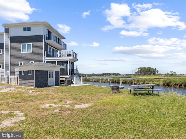 view of yard with a balcony, a water view, and an outdoor structure