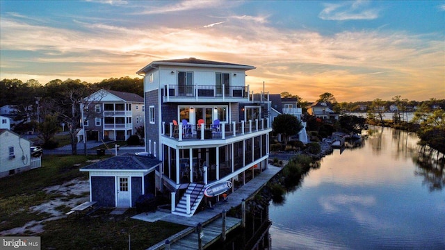 back house at dusk with a balcony and a water view