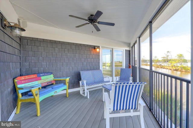 sunroom / solarium featuring ceiling fan and a water view