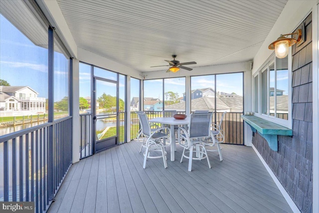 unfurnished sunroom featuring ceiling fan and a water view