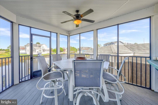 sunroom featuring a water view and ceiling fan