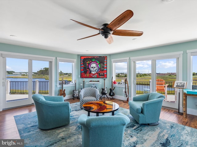 living room featuring ceiling fan, a water view, and a healthy amount of sunlight