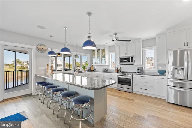 kitchen featuring a kitchen bar, white cabinetry, kitchen peninsula, and appliances with stainless steel finishes