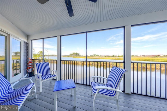 sunroom / solarium with ceiling fan and a water view