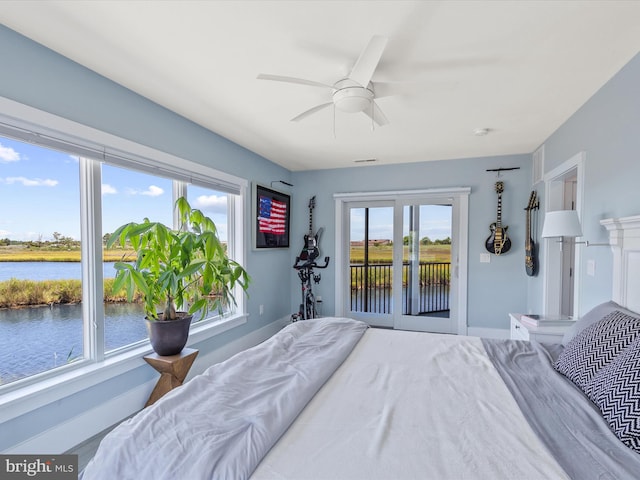 bedroom featuring access to exterior, multiple windows, a water view, and ceiling fan