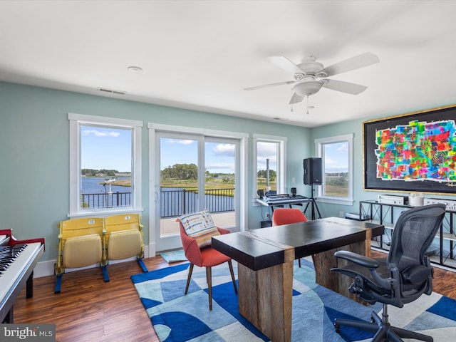 office with dark hardwood / wood-style flooring, ceiling fan, and a water view