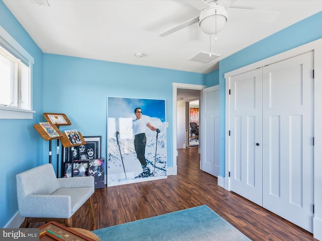 living area with ceiling fan and dark wood-type flooring