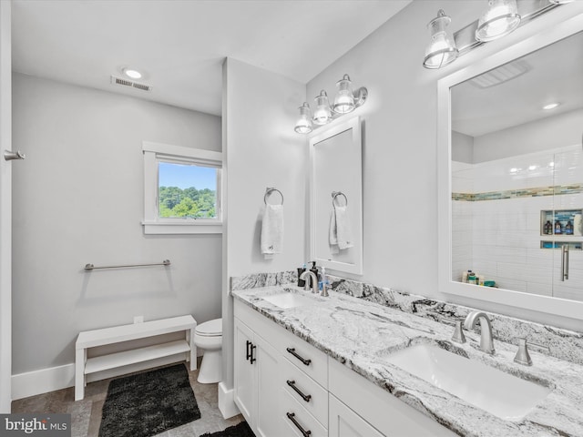 bathroom with a tile shower, vanity, and toilet