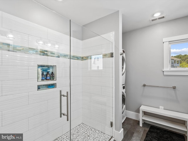 bathroom featuring stacked washer and dryer and a shower with door