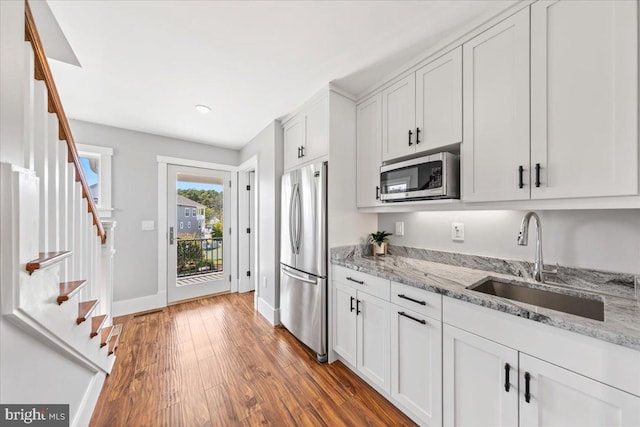 kitchen featuring dark hardwood / wood-style flooring, light stone counters, stainless steel appliances, sink, and white cabinetry